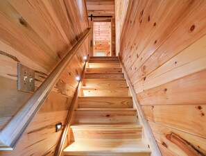 A wooden staircase with a handrail and wall-mounted light fixtures. - Beehive Bungalow *Charming Forest Escape* Hot Tub (Logan)