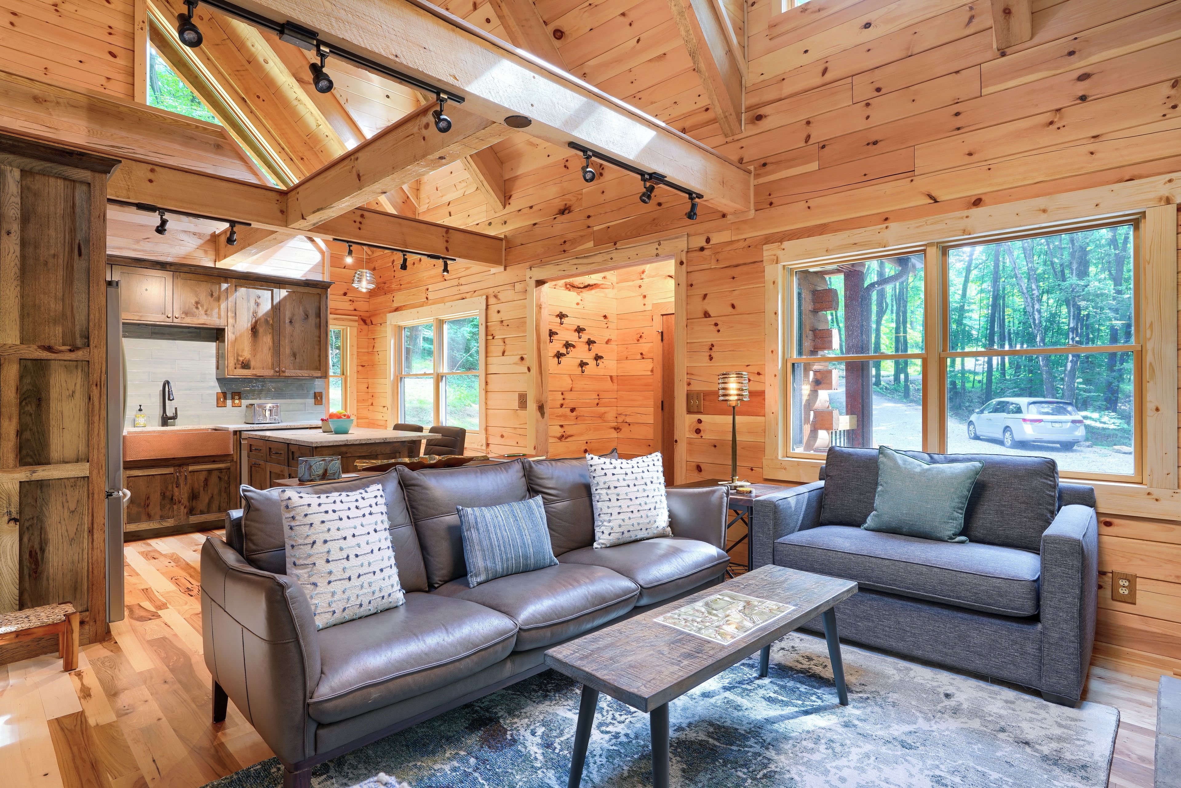 A cozy cabin interior with a sofa, a coffee table, and a dining area.