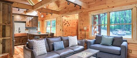 A cozy cabin interior with a sofa, a coffee table, and a dining area.