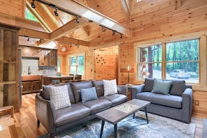 A cozy cabin interior with a sofa, a coffee table, and a dining area. - Beehive Bungalow *Charming Forest Escape* Hot Tub (Logan)