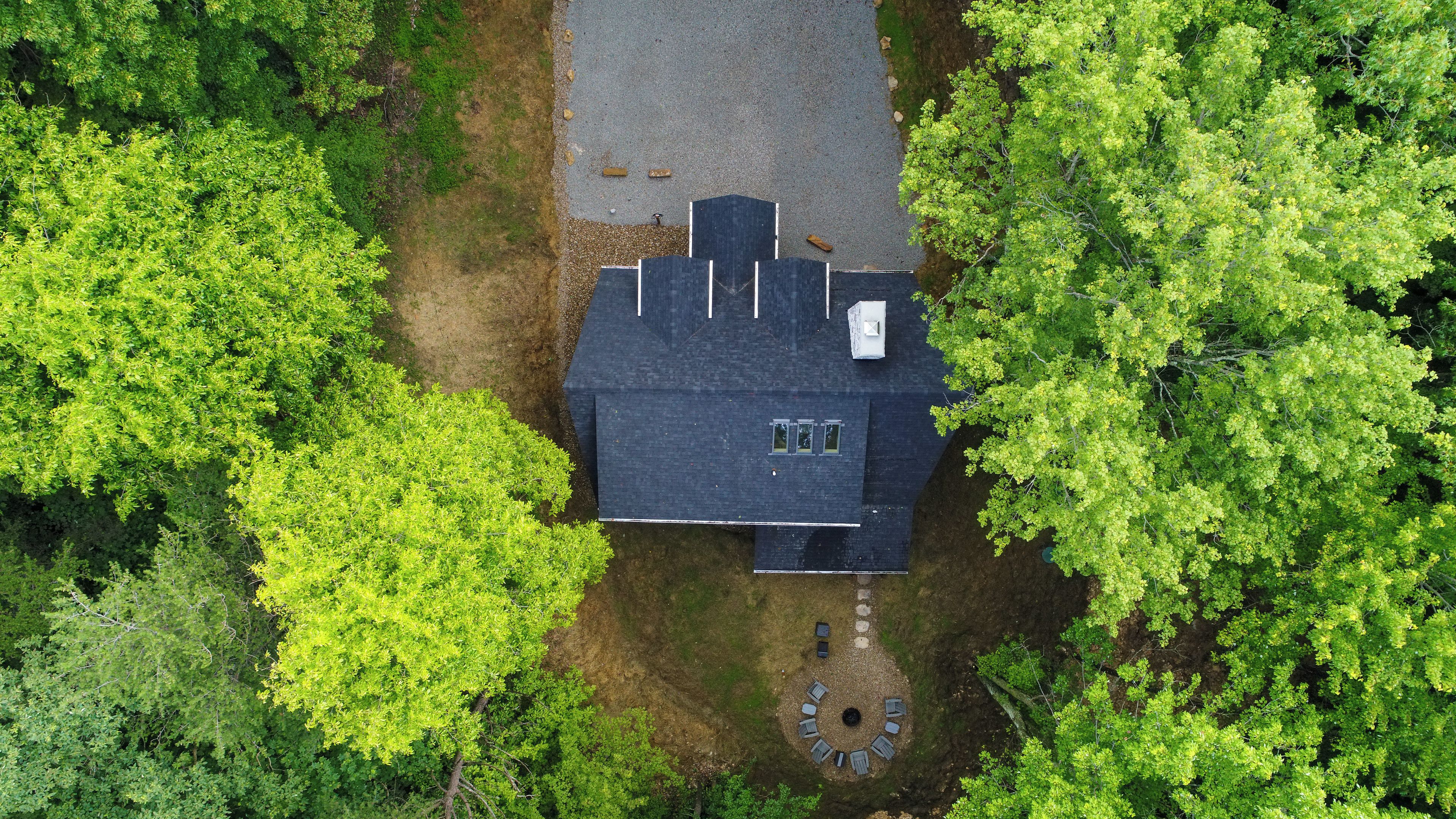 Una casa con techo oscuro, rodeada de árboles verdes y frondosos.