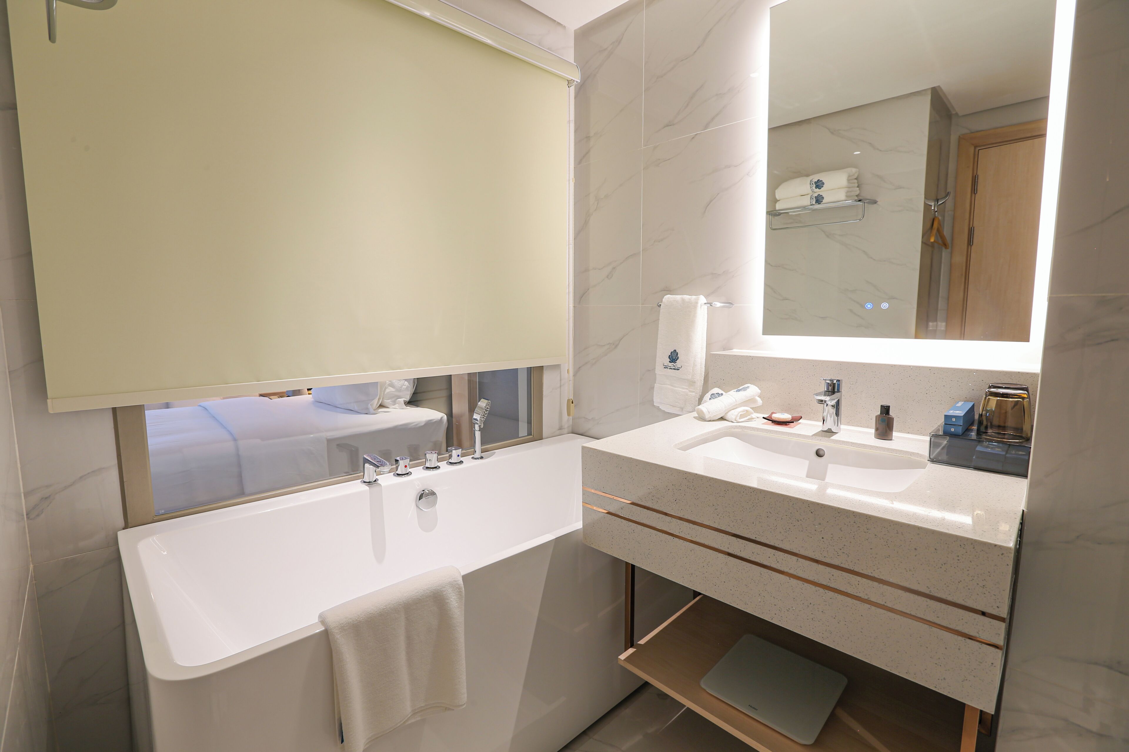A modern bathroom with a bathtub, a sink, a mirror, and a towel rack.