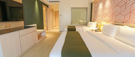 A hotel room with a bed, bedside table, lamp, TV, and a patterned wall.