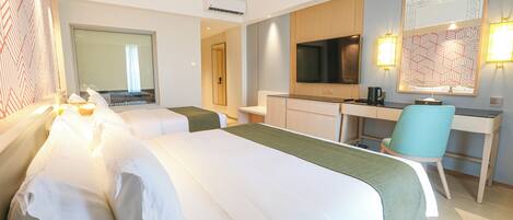 A hotel room with two beds, a desk, a chair, a TV, and a large mirror.