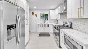 A modern kitchen with white cabinetry, stainless steel appliances, and gold handles. - Spacious 5-bedroom house in beautiful Downers Grove (Downers Grove)