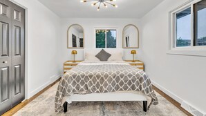 A bedroom with a bed, bedside tables, a bench, a chandelier, and a window. - Spacious 5-bedroom house in beautiful Downers Grove (Downers Grove)