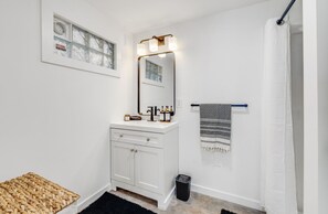 A bathroom with a white vanity, a mirror with lights, a towel rack, and a shower curtain. - Modern Loft in Vibrant Downtown Royal Oak - Just a Block Away! (Royal Oak)