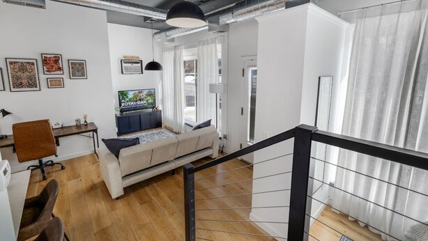A modern living room with a sofa, TV, and artwork on the wall. - Modern Loft in Vibrant Downtown Royal Oak - Just a Block Away! (Royal Oak)