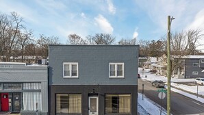 A two-story building with a dark facade, a red door, and a visible address number. - Modern Loft in Vibrant Downtown Royal Oak - Just a Block Away! (Royal Oak)