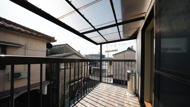 Un balcon doté d’un plancher en bois, d’une rambarde en métal et d’un toit en verre.