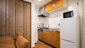 Une cuisine moderne avec des meubles en bois, un réfrigérateur blanc et un four à micro-ondes posé sur le dessus.