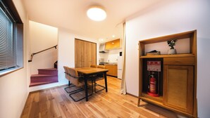 Une cuisine compacte avec un plancher en bois, un coin repas comprenant une table et des chaises, et un escalier menant à un autre niveau.