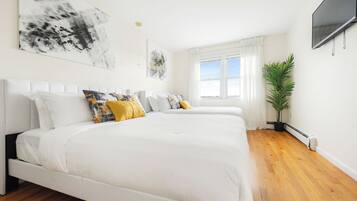 Quarto moderno com uma cama grande, planta em vaso e obras de arte nas paredes.