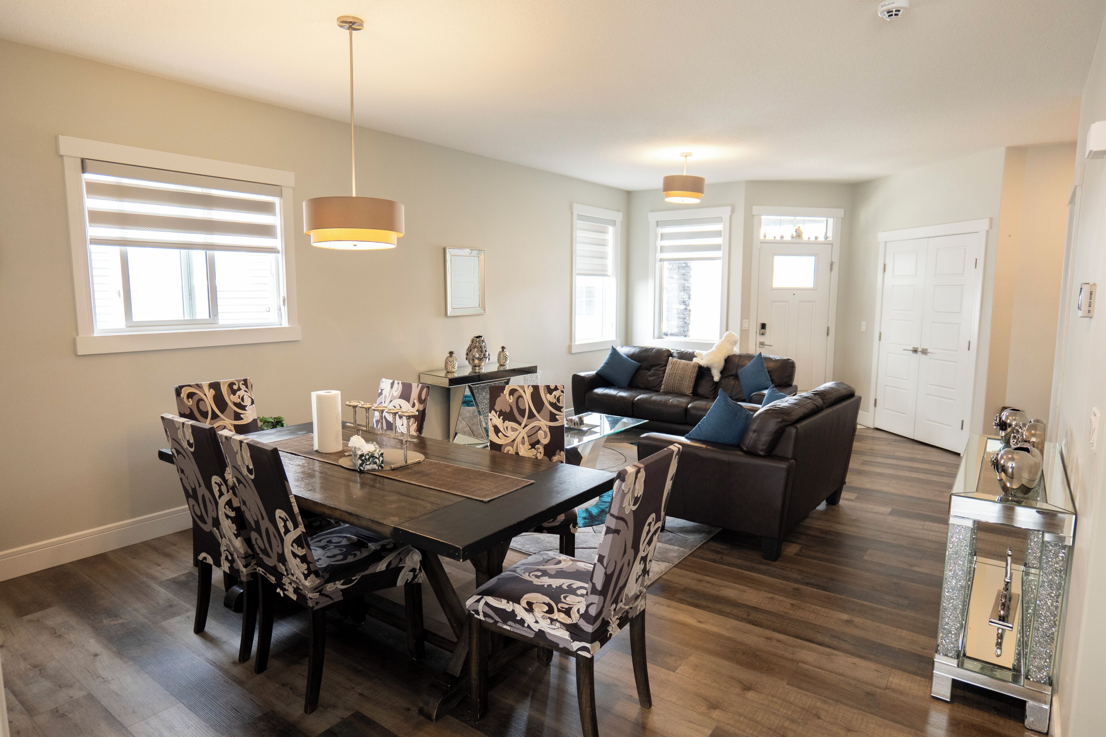 A dining area with a table, chairs, and a chandelier. There is a living room with a sofa and a coffee table.
