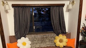 Ein gemütliches Zimmer mit einer hölzernen Bank, einem Haustierbett und einem Fenster mit Vorhängen.