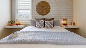 A bedroom with a bed, two bedside tables, a window, and a wall-mounted decorative item. - Private Pool, Shared Heated Pool, Outdoor Kitchen (Port Aransas)