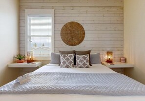 A bedroom with a bed, two bedside tables, a window, and a wall-mounted decorative item. - Private Pool, Shared Heated Pool, Outdoor Kitchen (Port Aransas)