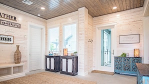 A room with wooden walls and ceiling, two doors, a bench, a rug, and a cabinet with decorative items. - Private Pool, Shared Heated Pool, Outdoor Kitchen (Port Aransas)