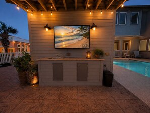 A poolside bar with a TV, outdoor seating, and a pool. - Private Pool, Shared Heated Pool, Outdoor Kitchen (Port Aransas)