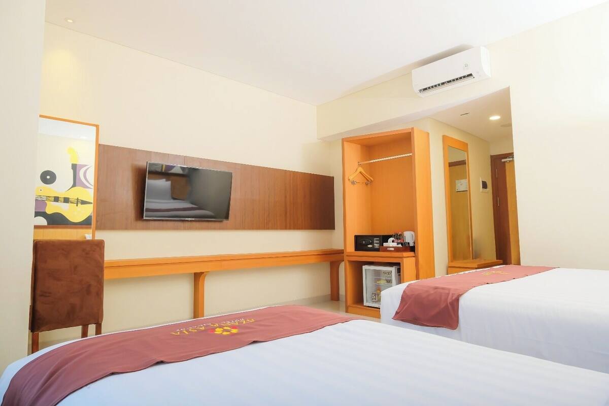 A hotel room with two beds, a TV, a minibar, and a shower area.