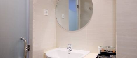 A modern bathroom with a white sink, a round mirror, and a door with a handle.
