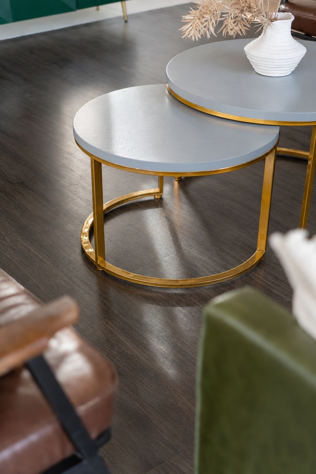 Two round tables with gold legs and grey tops, placed on a wooden floor.