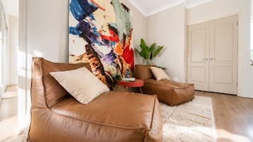 A modern living room with leather sofas, a large abstract painting, and a potted plant.