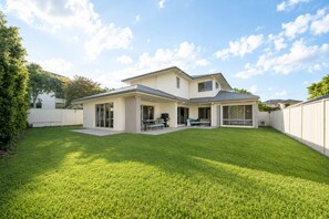 A modern two-story house with a covered patio, a fenced backyard, and a well-maintained lawn. - Family Friendly Funhouse close to All Theme Parks (Upper Coomera)
