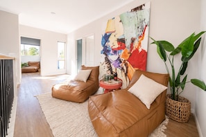 A modern living room with leather sofas, a large abstract painting, and a potted plant. - Family Friendly Funhouse close to All Theme Parks (Upper Coomera)