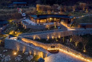 A modern building with a curved roof, stone pathways, and a panda statue with balloons. - Country Retreats Shaanxi Foping (Hanzhong)