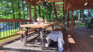 Una terraza de madera con mesa, bancos y una parrilla.