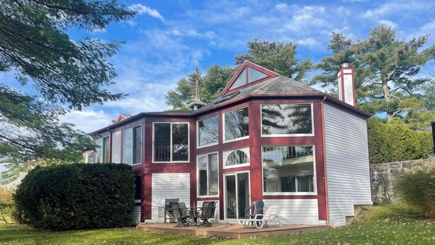Une maison à deux étages, avec une façade rouge et blanche, de grandes fenêtres et une cheminée.