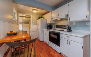 A kitchen with white cabinets, a wooden table, and a stove.