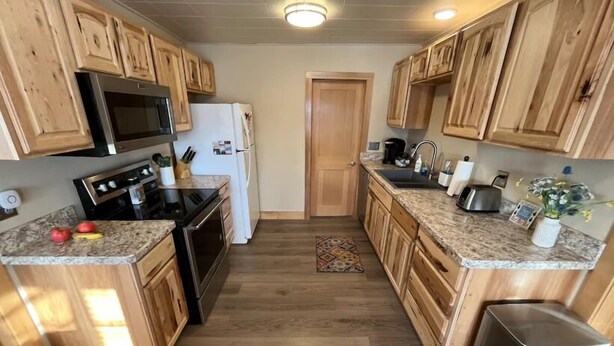 Una cocina con armarios de madera, un refrigerador de acero inoxidable, un microondas, una estufa y un lavabo.