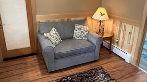 A grey sofa with patterned cushions, a wooden floor, a lamp with a deer design, and a patterned rug. - Welcome to Bleistein Studio- Your launchpad for adventure (Cody)