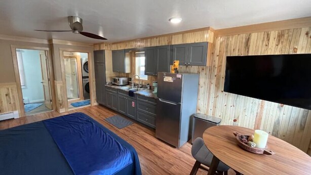 A compact kitchen with wooden cabinetry, a refrigerator, and a dining area with a table and chairs. - Welcome to Bleistein Studio- Your launchpad for adventure (Cody)