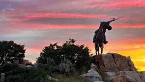 A statue of a person with a rifle on a rock formation with a sunset in the background. - Welcome to Bleistein Studio- Your launchpad for adventure (Cody)