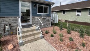 A two-story house with a stone facade, a front porch with steps, and a small garden with mulch and plants. - Welcome to Bleistein Studio- Your launchpad for adventure (Cody)