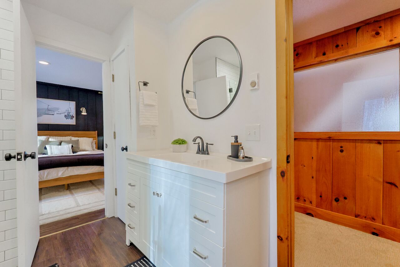 A bedroom with a bed, a white dresser, a mirror, and a small potted plant.