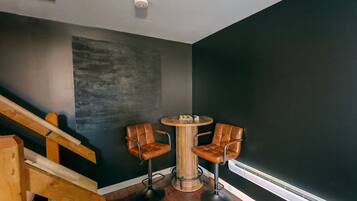Een moderne kamer met een trap, een ronde houten tafel met twee leren stoelen, en een accentmuur in het zwart.