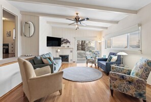 A spacious living room with a fireplace, a ceiling fan, and a large window. - Views of Lake Michigan - Pet friendly rental - Walking distance to beach (Grand Haven)