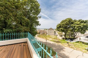 A residential area with a wooden deck, turquoise railing, and a view of houses and the sea. - Views of Lake Michigan - Pet friendly rental - Walking distance to beach (Grand Haven)