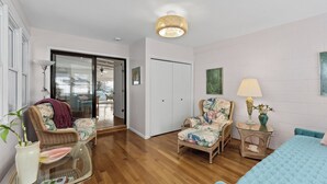 En stue med et glasbord, fletstole, en blå sofa og en lampe på et sofabord.