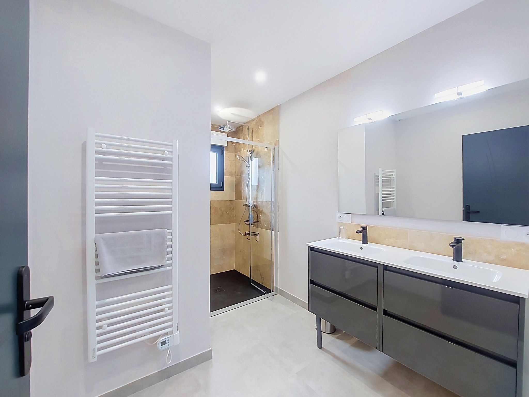A modern bathroom with a walk-in shower, a large mirror, and a vanity with a sink and cabinet.