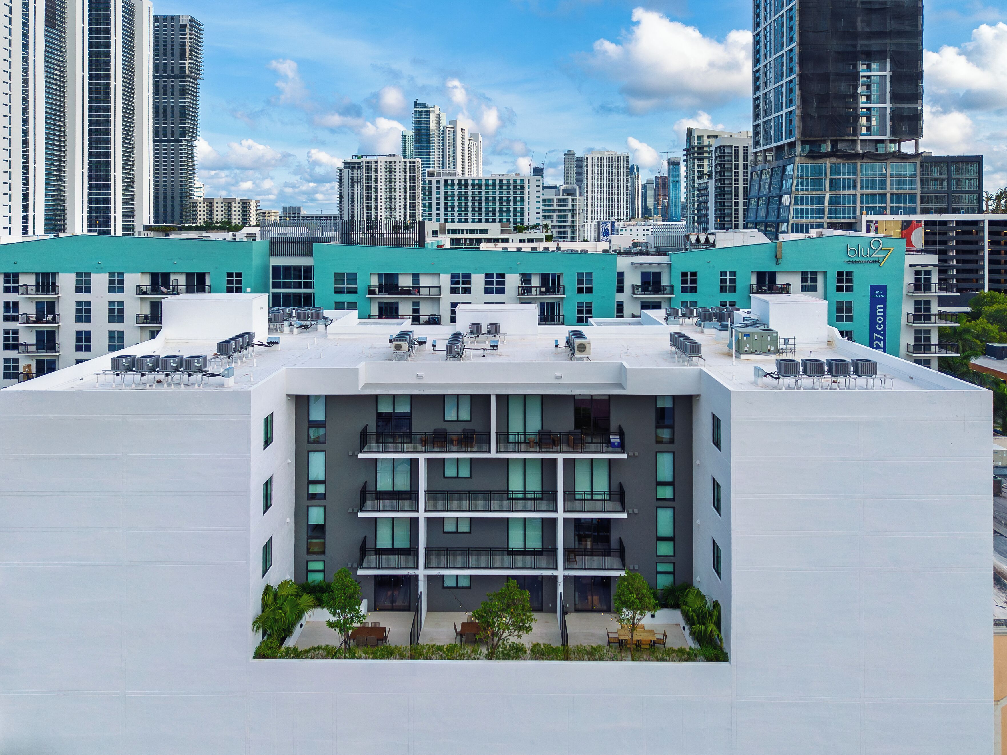 A modern building with multiple balconies, a rooftop terrace, and a view of the city skyline.