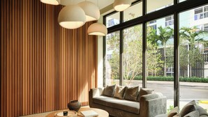 Un interior moderno con un sofá, una mesa de centro redonda de madera y ventanas amplias con vistas a la calle.