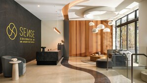 Un moderno vestíbulo de hotel con mostrador de recepción, zona de estar y grandes ventanales.