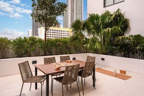 A rooftop terrace with a dining table, chairs, and a board game.