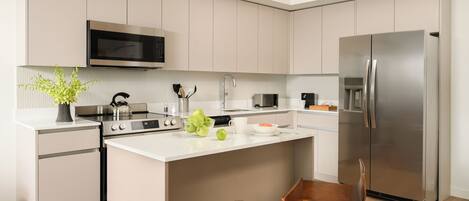 A modern kitchen with a central island, stainless steel appliances, and wooden chairs.