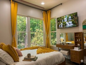 A bedroom with a bed, a desk, a television, and large windows with curtains. - Creekside Mountain Family Retreat (Mills River)